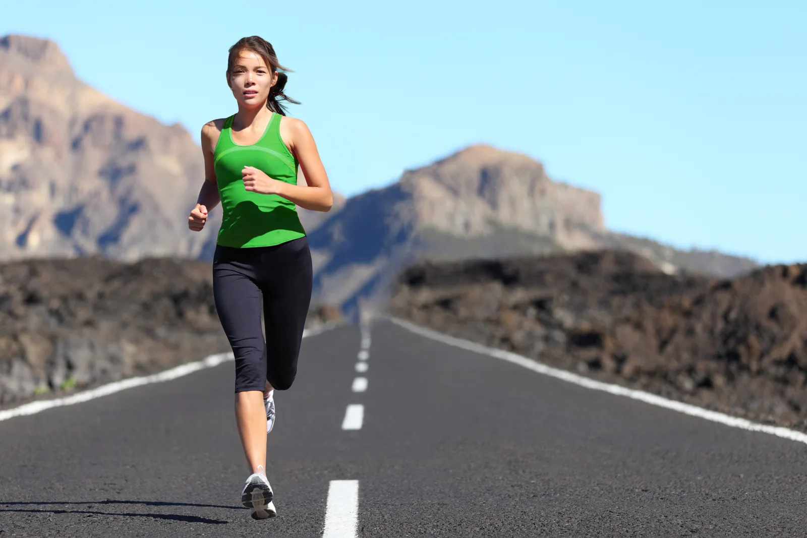 A runner striding out fast and controlled on a flat, quiet open road