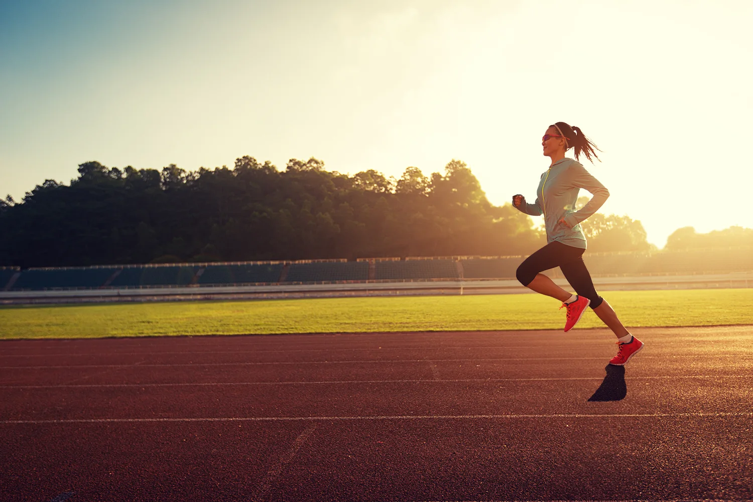 A runner striding fast and relaxed on a track at golden hour